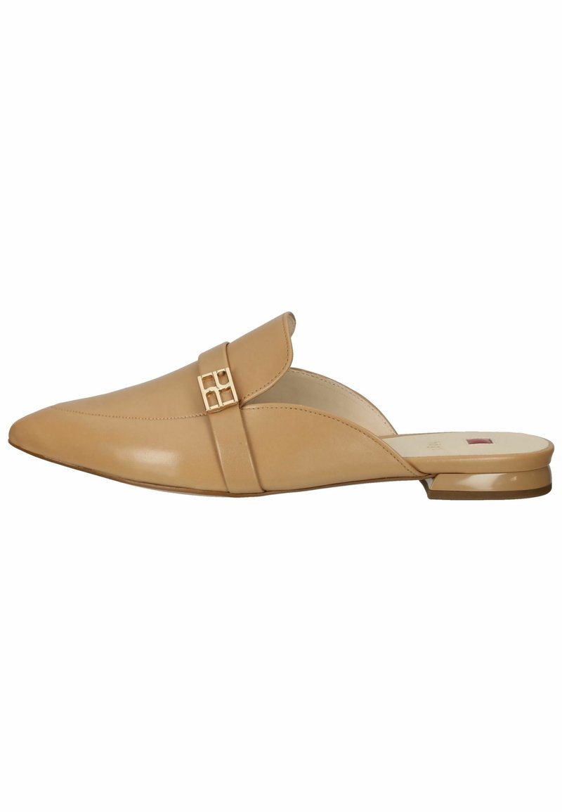 Mule en cuir beige avec un bout pointu, un talon plat, une sangle chevauchante et un accent métallique décoratif arborant un motif géométrique.