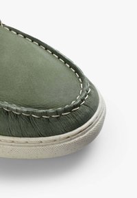 Scarpa in pelle verde con superficie testurizzata, cuciture dettagliate e suola in gomma bianca. Design con punta arrotondata e pieghe visibili.