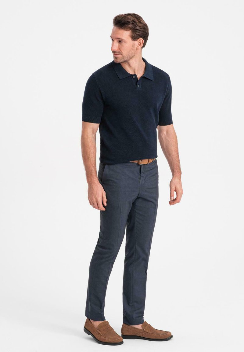 Mörkblå kortärmad polo med en texturerad mönster, kombinerad med skräddarsydda mörkblå byxor och bruna mockaloafers.