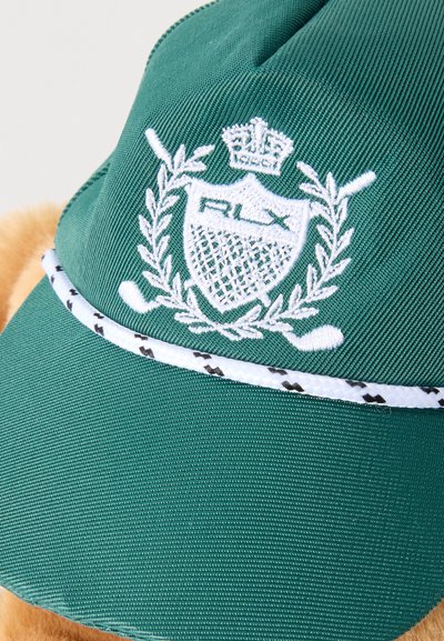 Grüne Baseballkappe mit weißem gesticktem Wappen, das eine Krone, gekreuzte Golfschläger, einen Lorbeerkranz und ein strukturiertes Schilddesign zeigt.