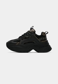 Černá sportovní teniska s mesh panely, texturovanou gumovou podrážkou, zaobleným tvarem a výrazným logem po straně a na patě. Lehký design.