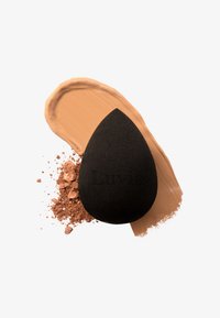 Spugna per trucco nera a forma di lacrima, con una texture liscia. Accompagnata da crema trucco marrone e cipria libera su sfondo bianco.