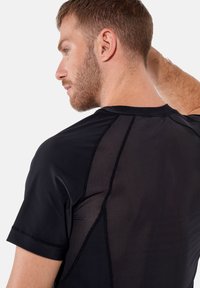 Svart atletisk T-shirt med nätpaneler på baksidan, korta ärmar, rundad halsringning och kontrasterande sömmar.