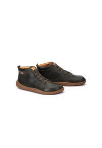 Zapatos altos de cuero verde oscuro con suelas de goma marrón, que cuentan con cordones y un forro interior acolchado. Los acentos laterales realzan el diseño.