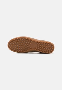 Semelle de chaussure avec un motif de bande de roulement en caoutchouc naturel comprenant de petits crampons carrés et le logo Nike au centre.