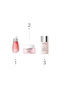 Drei Hautpflegeprodukte nebeneinander angeordnet: eine rosa flüssige Serumflasche, ein runder rosa Cremetiegel und eine hellrosa Lotionflasche mit silberner Kappe.