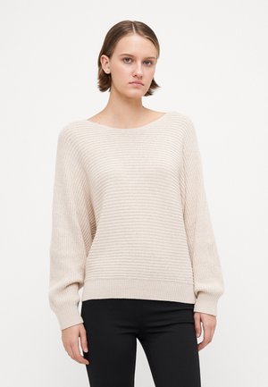 Beige knit sweater with wide neckline, ribbed texture, and long sleeves, paired with black pants. Simple design and lightweight material.