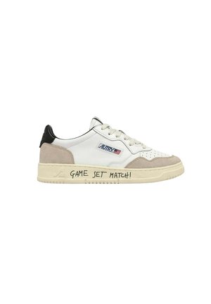 Sneaker bassa bianca con dettagli in camoscio beige, linguetta nera sul tallone, patch con logo Autry e scritta "GAME SET MATCH!" sul lato della suola.