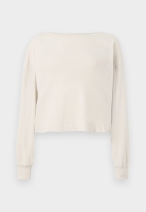 Langermet, off-white cropped genser med bred utringning og ribbestrikkede mansjetter på hvit bakgrunn.