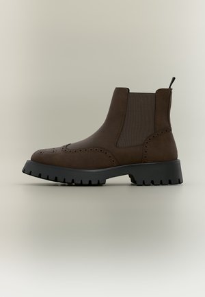 Dunkelbrauner Leder-Chelsea-Stiefel mit Brogue-Details, elastischen Seitenpaneelen, Zuglasche und dicker schwarzer Gummisohle mit tiefem Profil.