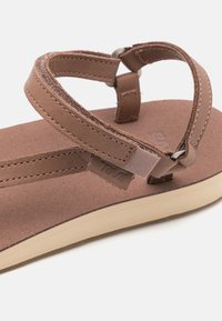 Brown leather sandal with two straps and a soft footbed, featuring a tan rubber sole and branded detail on the side.