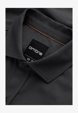 Mørkegrå polo t-shirt med spids krave, knaplukning og et mærke med "ombre." Blød, glat tekstur, klassisk design.