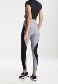 Szare i czarne legginsy sportowe o fakturowanym, dopasowanym kroju z gładkimi panelami. W zestawie z czarnym, prążkowanym topem crop i czarnymi sneakersami.