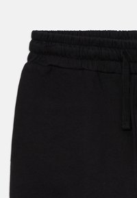 Schwarze Sweatpants mit elastischem Bund und Kordelzug, aus weichem Stoff gefertigt, von der Taille bis zur Mitte des Oberschenkels auf einem weißen Hintergrund gezeigt.