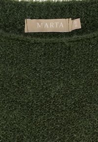 Mörkgrön, strukturerad stickad tröja med en mjuk, lurvig yta. Har en etikett märkt "MARTA" i ljusbeige tyg vid halsringningen.