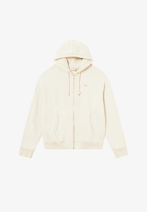 Haut à zip crème avec capuche à cordon de serrage, poches kangourou, poignets et ourlet côtelés. Présente un petit logo brodé sur la poitrine.