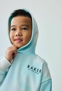 Sudadera azul claro con un patrón desgastado, cuenta con un bolsillo frontal y puños acanalados. Logo "BAKER by TED BAKER" impreso en el pecho.