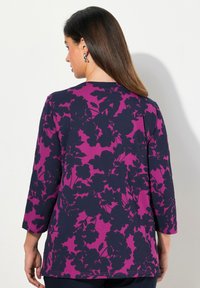 Długo rękawowy top w granatowym kolorze z fioletowym wzorem kwiatowym, okrągły dekolt i luźny krój. Miękki materiał z lekkim streczem dla wygody.