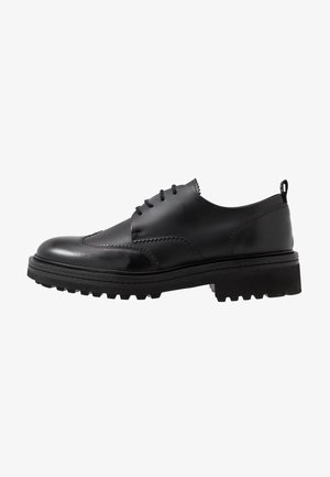 Zwarte leren veterschoen met dikke profielzool en gestikte details, zijaanzicht.