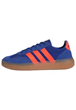 Blauwe en oranje lage sneaker met drie oranje strepen aan de zijkant en een transparante gumzool.