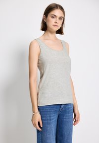 Top senza maniche grigio chiaro in morbido tessuto, con scollo rotondo e cuciture laterali. Abbinato a jeans a gamba larga blu.