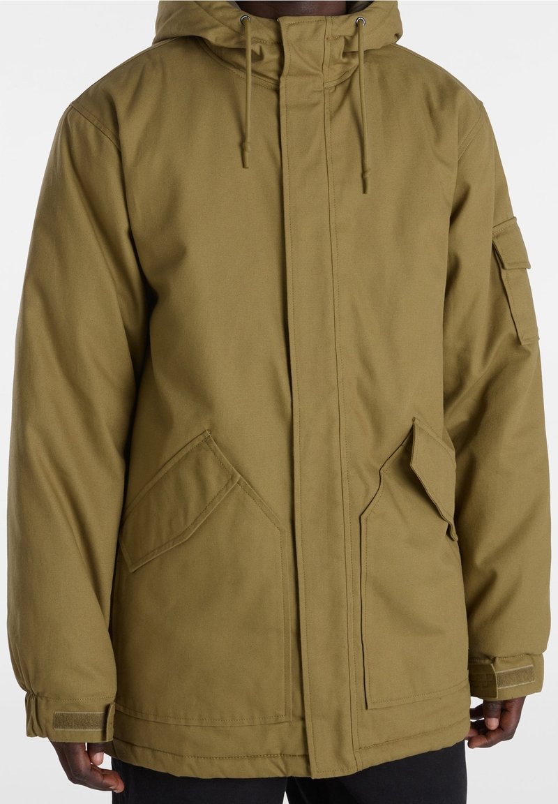 Olive green parka jacket with a hood, featuring two front pockets, adjustable drawstrings, and a textured fabric. Includes sleeve pocket detail.