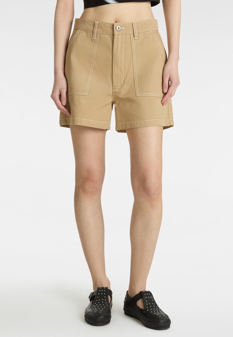 Shorts de tiro alto en color beige, con un diseño estructurado y bolsillos frontales, que presentan detalles de costura blanca. El material parece resistente y texturizado.