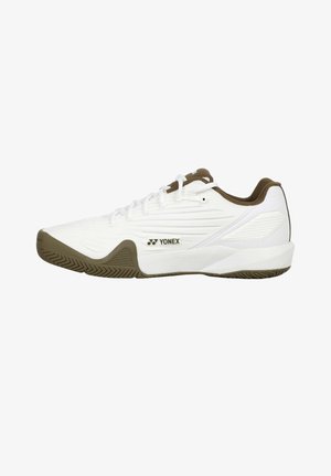 Witte Yonex sportschoen met bruine zool en binnenvoering, veterontwerp en getextureerde zijkant voor grip en ondersteuning.