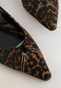 Ballerines à imprimé léopard avec un design à bout pointu, en tissu texturé avec des motifs noirs et marron, et un intérieur noir épuré.