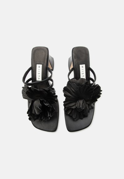 Μαύρα σανδάλια με τακούνι, τετράγωνες μύτες, διπλά λουράκια και μεγάλα διακοσμητικά με λουλούδια με βολάν μπροστά.