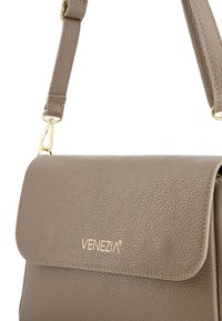 Szara skórzana torebka o teksturowanym wykończeniu, z klapą i złotym logo. Posiada regulowany pasek z złotymi akcentami.