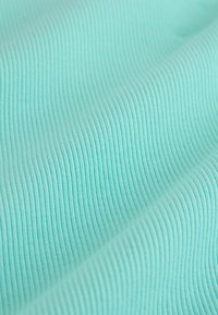 Tissu côtelé turquoise clair avec une texture douce et de fines lignes verticales, présentant des ondulations et des plis qui soulignent sa flexibilité.