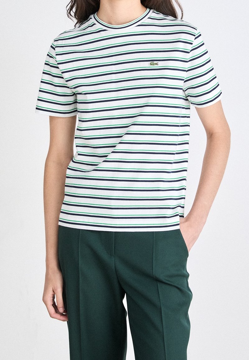 Randig t-shirt med horisontella linjer i marinblått, grönt och vitt, tillverkad av bomull med rundad hals och en liten broderad logotyp.