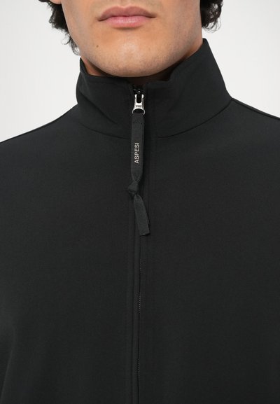 Čierna zipsová bunda vyrobená z hladkej látky, s vysokým golierom a predným zipsom s ťahákom a malou značkovou etiketou.
