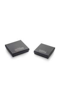 Två fyrkantiga svarta lådor, en större och en mindre, tillverkade av matt material, med texten "TRUE REBELS!" i en kontrasterande silverfärg på toppen.