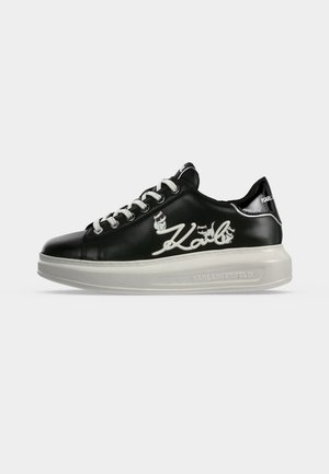 Μαύρο sneaker χαμηλής κοπής με λευκή σόλα, λευκά κορδόνια και λευκή "Karl" γραφή με μικρά σχέδια γατών στην πλευρά.