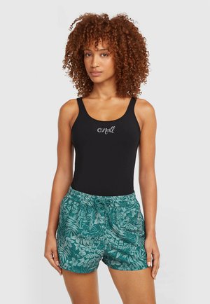 Juodas vientisas maudymosi kostiumėlis su logotipu krūtinės srityje, derinamas su turkio spalvos šortais su baltais tropinių lapų raštais ir elastinga juosmens juosta.