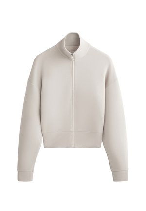 Zkrácená, světle béžová mikina na zip s vysokým límcem, spadlými rameny a žebrovanými manžetami, vyrobená z měkké, texturované látky.