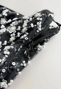 Schwarze Netz-Clutch mit silbernen Pailletten und Perlen, ausgestattet mit einem Reißverschluss und einer strukturierten Oberfläche mit floralen Mustern aus Verzierungen.