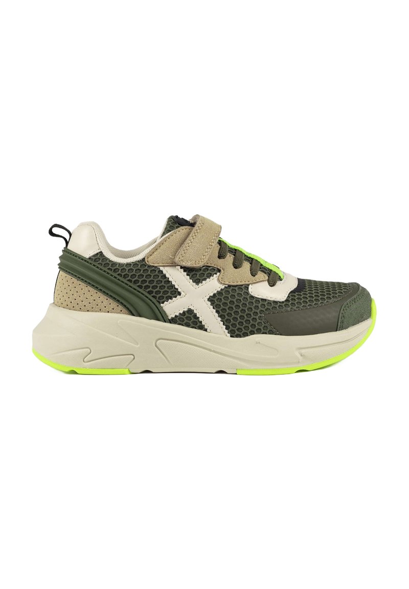 Zapatillas deportivas verdes y beige con parte superior de malla, acentos blancos, tira de Velcro y suela verde. Presentan un acabado texturizado y un diseño ligero.