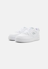 Fehér sneaker, sima bőrből készült felsőrésszel, kerek orr résszel, fűzős záródással és zöld logóakkcentussal. Ventilációs perforációkkal és gumitalppal rendelkezik.