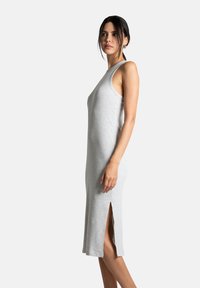 Robe sans manches à rayures grises avec une fente sur le côté, conçue pour une silhouette ajustée. Texture douce et longueur décontractée jusqu'au mollet.