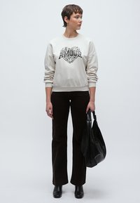 Ανοιχτό γκρι φούτερ με σχέδιο καρδιάς και τη λέξη "AMOUR" σε μαύρο. Συνδυασμένο με σκούρο καφέ φαρδιά παντελόνια και υφή στο μαύρο τσαντάκι.