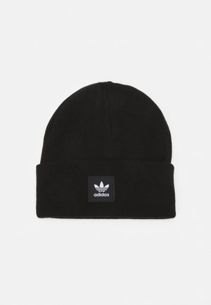 Sort strikket hue med en foldet manchet, der har et firkantet sort mærke med Adidas-logoet i hvidt. Blød tekstur, varmt materiale.