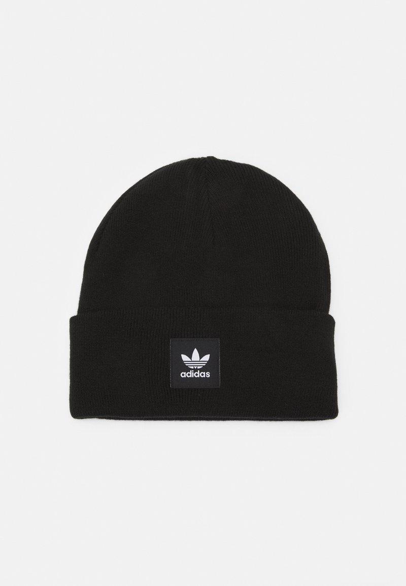Zwarte gebreide muts met een opgevouwen rand, voorzien van een vierkante zwarte label met het Adidas-logo in het wit. Zachte textuur, warm materiaal.