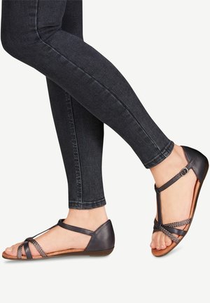 Mørke lædersandaler med krydsremme, T-rem-design og en polstret indersål. Sålen er flad med en let hæl.