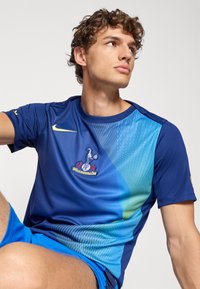 Blå Nike sports t-shirt med en gradientdesign og lyseblå accenter, korte ærmer og et broderet logo på brystet.