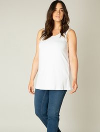 Witte mouwloze top met een ronde halslijn, gemaakt van zachte stof, gecombineerd met blauwe skinny jeans, met een zijsplit voor gemakkelijke beweging.