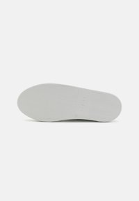 Fehér sneaker talp halcsontos mintával és dombornyomott márkanevével. A méret 37-es, sima textúrájú, minimalista dizájnnal.