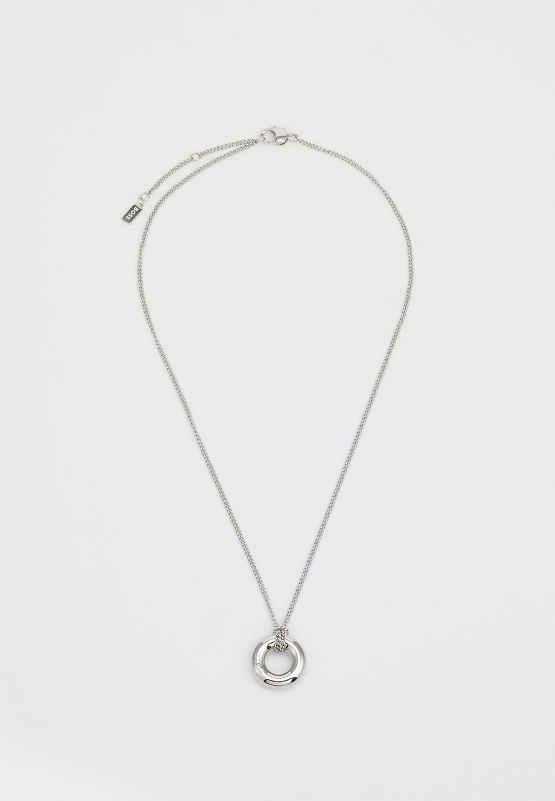 Silver chain necklace featuring a double circular pendant with a textured center and a clasp closure. Accented with a small tag.